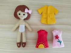 three felt doll clothes are laid out on a wooden surface, one is yellow and the other has pink