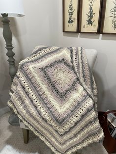 there is a crocheted blanket that is on the chair next to a lamp