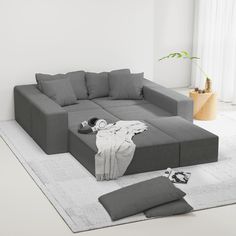 a living room with a large gray couch and ottoman on the floor next to a potted plant