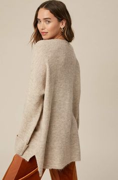 So chic and effortless, this slouchy, oversized tunic-style sweater features a v-neckline and dropped wide sleeves for added shape. -Available in Stone & Misty Blue -Waffle textured -V-neck -Oversized fit -Soft touch eyelash two tone yarn -Long sleeve with folded cuffs -Side slits -Ribbed on hem -Content: 74% Acrylic 22% Polyester 4% Lycra -Hand was cold/Line dry -Imported -Model is 5 8" 32-24-34 and wearing a size Small Oversized Chic V-neck Sweater For Layering, Chic Oversized V-neck Sweater For Layering, Oversized V-neck Sweater For Fall, Oversized V-neck Chic Sweater, Oversized V-neck Sweater For Everyday Fall Wear, Oversized V-neck Sweater For Loungewear, V-neck Sweater For Loungewear In Fall, Oversized V-neck Sweater With Soft Texture, Oversized Chic Sweater With Ribbed Neckline