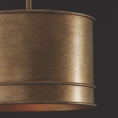 a gold colored lamp hanging from a ceiling fixture in a dark room with dim lighting