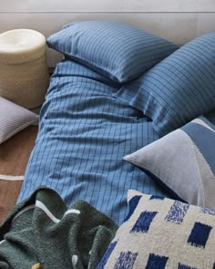 an unmade bed with blue and white pillows