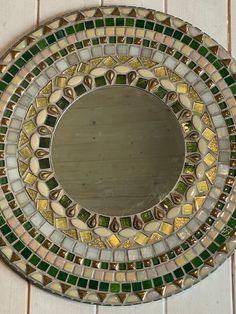 a round mirror sitting on top of a tiled wall next to a wooden flooring