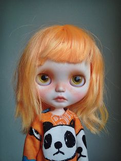 a doll with orange hair wearing an orange shirt and panda bear t - shirt on