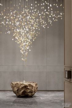 a large chandelier hanging from the ceiling over a stone bowl in a room