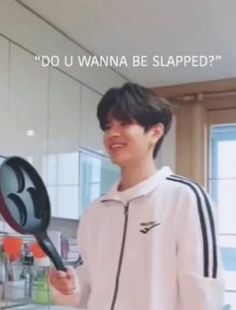 a young man holding a frying pan in front of a kitchen counter with the words do u wanna be slapped?