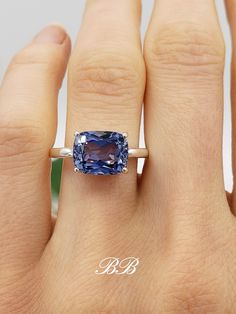 a woman's hand with a blue ring on it and a tan diamond in the middle