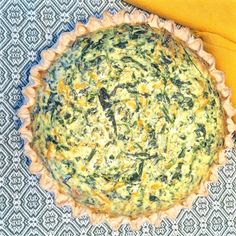 a quiche with spinach and cheese in a pie pan next to a banana