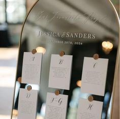 a mirror with seating cards attached to the front and back of it in gold frame