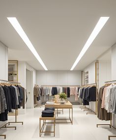 an empty clothing store with clothes hanging on racks and tables in front of the counter