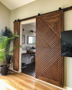 a living room with sliding doors and a tv on the wall next to a potted plant