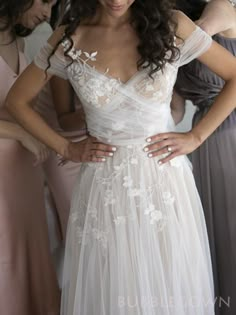 a woman in a white wedding dress standing next to other women