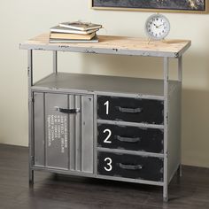 a metal table with drawers and a clock on the wall next to it in front of a painting