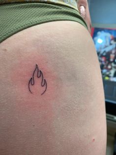 a small tattoo on the back of a woman's thigh, depicting a fire