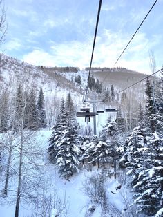 a ski lift going up the side of a snow covered mountain with trees on both sides