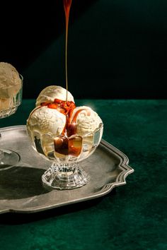 two ice cream sundaes sitting on top of a silver tray