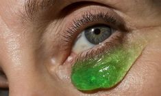 a woman with green eyeliners on her eyes and the bottom half of her eye