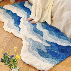 a woman sitting on the floor in front of a blue and white rug with waves