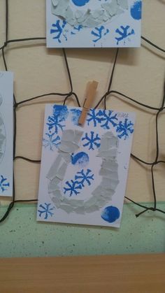 two pieces of paper are taped to the wall with clothes pins and snowflakes on them