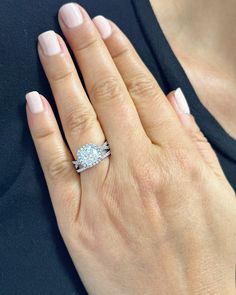 a woman's hand with a diamond ring on top of her finger and the other hand holding an engagement ring