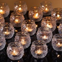 there are many clear glass jars with lit candles in them