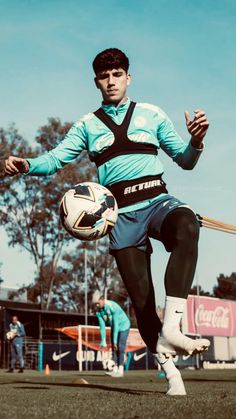 a man kicking a soccer ball on top of a field