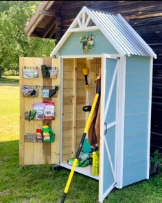 a shed that has some tools in it and is sitting on the grass with its door open