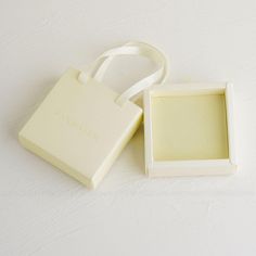 a small white box with a ribbon around it and an empty square in the middle