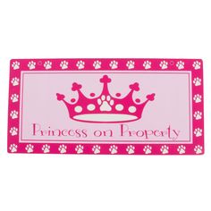 a pink door mat that says princess on property with paw prints and a crown in the center