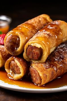 some sausage rolls are on a plate with syrup