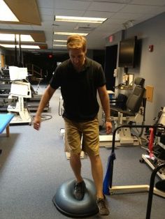 a man standing on an exercise ball in the middle of a room with other equipment