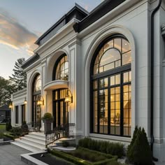 a large white house with many windows and steps leading to the front door at sunset