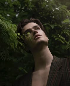 a man standing in front of green leaves