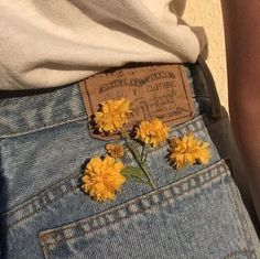 yellow flowers sticking out of the back pocket of someone's jeans