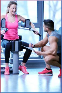 a man and woman sitting on exercise equipment in a gym with one holding a clipboard