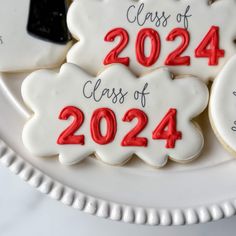 decorated cookies on a white plate with the words class of 2024 printed on them