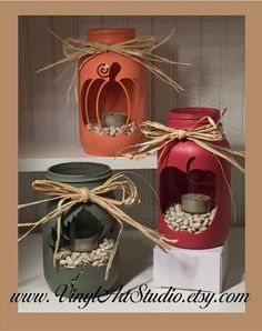 three mason jars decorated with pumpkins and candles