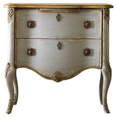 an ornate white and gold chest of drawers with brass accents on the top, against a white background