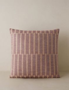 a pink and brown pillow sitting on top of a white table next to a wall