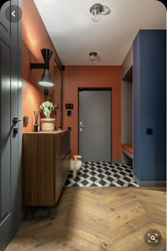 an orange and blue hallway with wooden flooring, black accents and white checkered tile