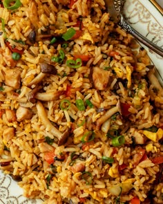 a plate full of rice and vegetables with a fork next to it on a table