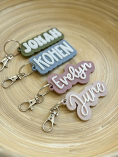 four keychains with name tags on them sitting in a wooden bowl next to each other