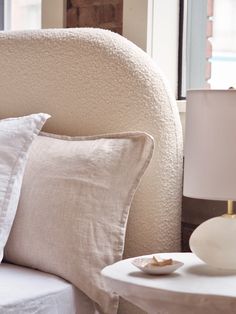 a bed with white linens and pillows next to a window