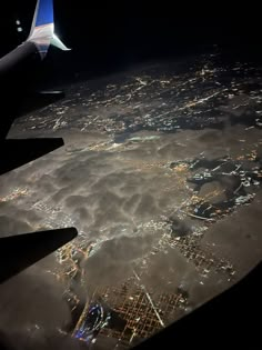 an airplane wing flying over the city lights