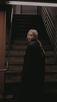 a woman standing at the bottom of an escalator