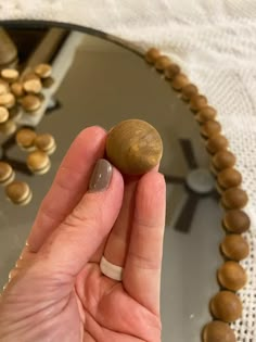 a person holding a rock in front of a mirror with other rocks around it on a table