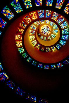 a spiral stained glass window in the center of a room with multiple colors on it