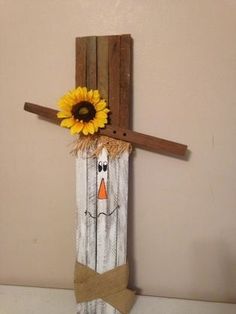 a scarecrow with a sunflower on it's head hangs from a wall