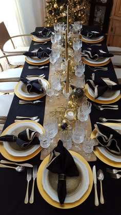 the table is set with black and gold place settings