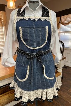 an apron made out of denim with lace on the bottom and back, sitting on a mannequin